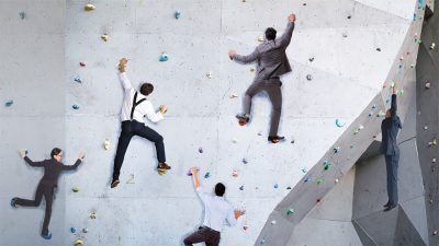 men in suits ascending a climbing wall